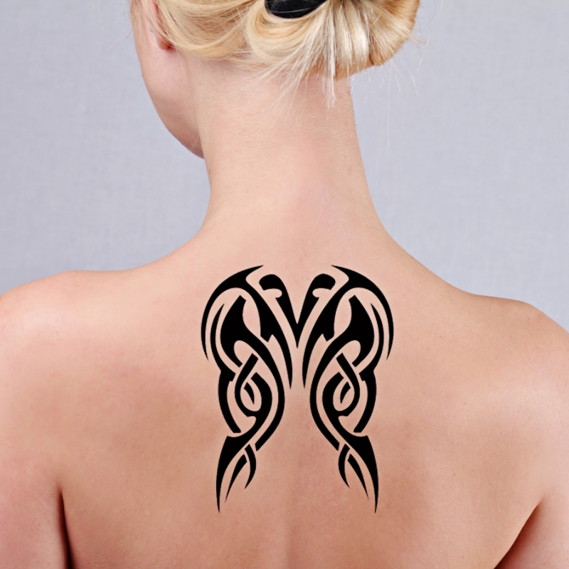 A female patient with a beautiful tattoo on her back before the laser tattoo removal treatment.