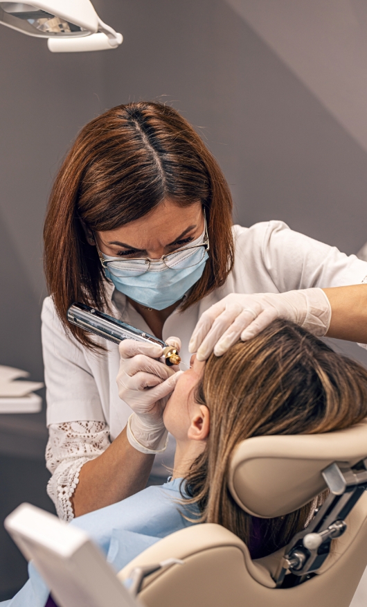 A cosmetic dermatologist uses a pulsed dye laser for treating birthmark removal on a patient.
